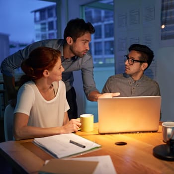 Planning, night and a business team on a laptop, working in the boardroom for teamwork, strategy or innovation. Meeting, strategy or overtime with a group of employees at work together in the evening.