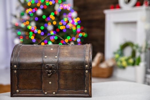 In front you can see an old brown box and against the fuzzy background stands a Christmas tree decorated with glowing Christmas tree lights.
