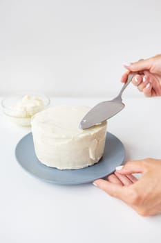 Delicious creamy cake that the girl spreads over the whipped cream with a spatula, the cake is ready for decoration