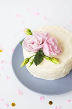 Very beautiful small white cake decorated with fresh eustoma flowers. Holiday concept