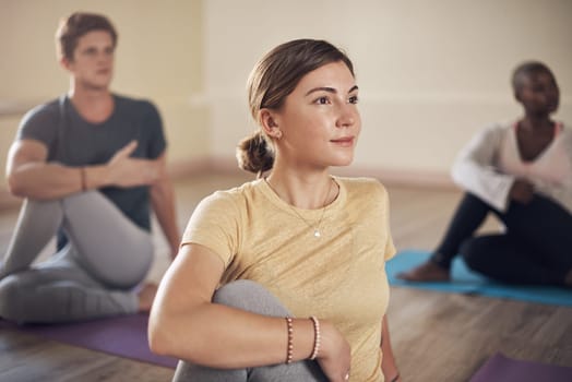 Yoga is a mirror to look at ourselves from within. a diverse group of yogis holding a spinal half twist pose during an indoor yoga session