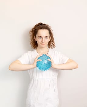 Rehabilitation Specialist, Physical Therapist In White Medical Clothes Holds Massage Ball With Pimples In Therapeutic Cabinet. Health Specialist, Rehabilitation. Vertical. High quality photo