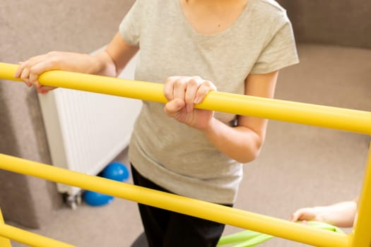 Cropped Disabled Teenage Girl With Doctor Does Physical Exercises In Rehabilitation Room. Child With Special Needs. Rehabilitation. Cerebral Palsy. Motor Disorder. Horizontal plane.High quality photo