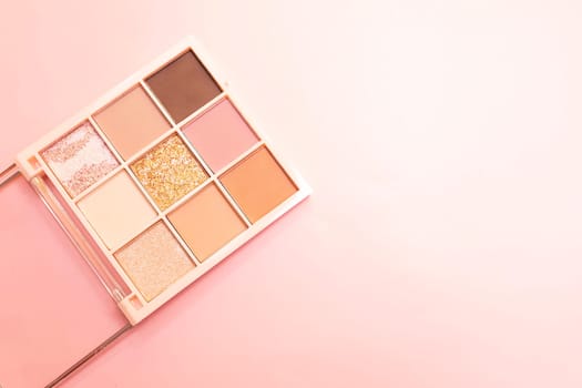 Eyeshadow multicolored palette cosmetics for eyes, face on pink background. Minimalism makeup, delicate shades. Copy space for text on right side, horizontal plane, flat lay. High quality photo