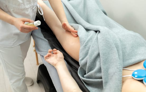 Cropped Doctor Gives Manual Massage To A Patient With Athetosis Disorder. White Woman Is Lying On Couch In Medical Room. Closeup, Horizontal Plane. High quality photo