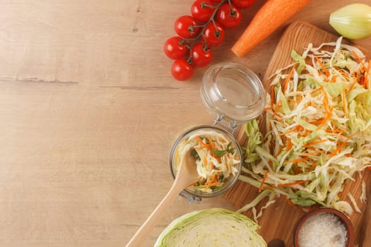 Cabbage lies on a wooden board with carrots, onions, herbs and cherry tomatoes. Preparing to cook cabbage dishes. copy space