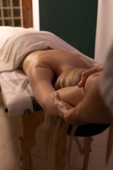 Male masseur, therapist pulls, stretches hands of white woman, client during professional therapeutic massage in spa salon. Mental, health sustainability. Relaxation, healthcare. Vertical plane