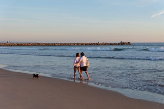 Young couple walking along the seashore. Mid shot