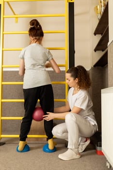 Disabled Teenage Girl With Doctor Does Physical Exercises In Rehabilitation Room. Child With Special Needs. Rehabilitation. Cerebral Palsy. Motor Disorder. Vertical plane. High quality photo