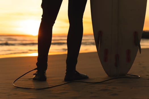 Surfboard tied to a man's leg at sunset. Mid shot