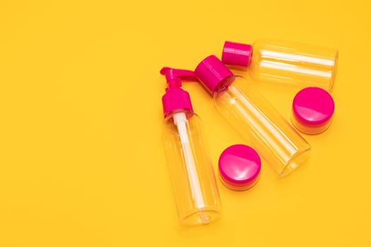 Top view travel bottle kit for liquids, cream. Toiletries Beauty Kit on yellow orange background. Airplane approved luggage reusable container size. Summer time, vacation. Horizontal. Copy space.