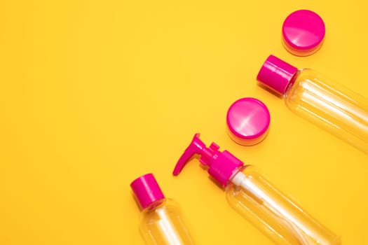 Flatly fuchsia travel bottle kit for liquids, cream. Toiletries Beauty Kit on yellow orange background. Airplane approved luggage reusable container size. Summer time, vacation. Horizontal. Copy space