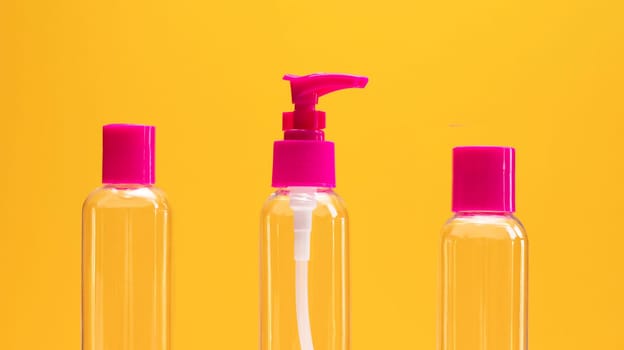Closeup fuchsia travel bottle kit for liquids, cream. Toiletries Beauty Kit on yellow orange background. Airplane approved luggage reusable container size. Summer time, vacation concept. Horizontal.