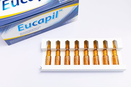 Eucapil box, fluridil lotion in set of ampules, cosmetic product for topical use in androgenetic alopecia, hair loss on blue background. Close up, horizontal. Bialystok, Poland: 22.02.2023 High quality photo