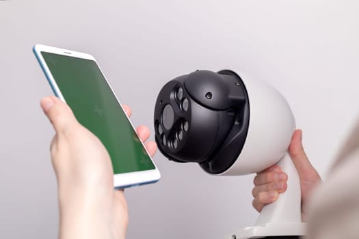 Surveillance IP Video Wireless Camera, Chroma Key Green Screen of Smartphone On Gray Background. Security Equipment For Smart Home with Online Remote App Monitoring, Control. Horizontal plane.