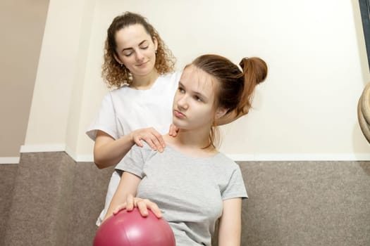 Rehabilitation Specialist, Physical Therapist Gives Neck Massage To Child, Teenage Girl With Disability. Health Specialist, Rehabilitation. Musculoskeletal Disorder.Horizontal plane.High quality photo