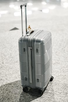 Gray travel suitcase in empty airport hall, close up