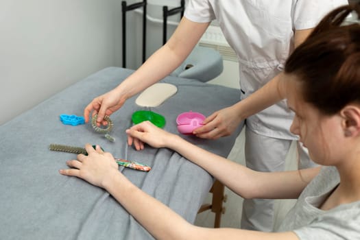 Female, Teenager with Disability Stretches Fingers With Physical Therapy Equipment. Health Specialist, Rehabilitation Of Cerebral Palsy, Athetosis. Horizontal plane, Closeup