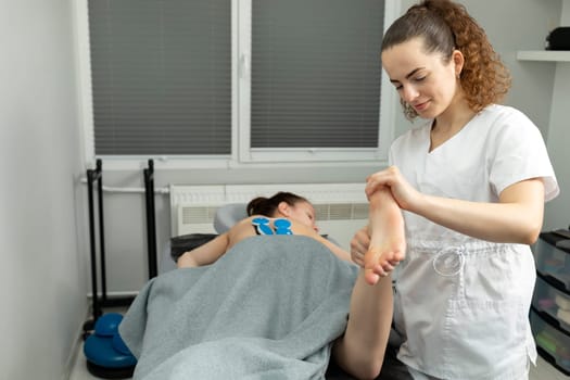 Rehabilitation Specialist, Physical Therapist Makes Foot Massage To Child With Cerebral Palsy, Scoliosis. Health Specialist, Rehabilitation. Horizontal plane. High quality photo