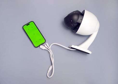 Surveillance IP Wireless Camera, Chroma Key Green Screen of Smartphone On Gray Background. Security Equipment For Smart Home,Online Remote App Monitoring.Protection Of Residential Building.Horizontal
