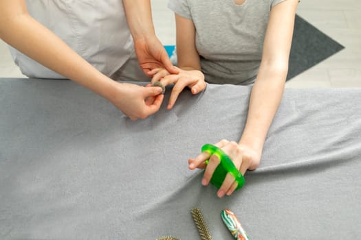 Cropped Doctor Neurologist Stretches Fingers Of Female Young Girl with Disability. Physical Therapy Equipment, Cerebral Palsy, Athetosis. Health Specialist, Rehabilitation. Horizontal plane.