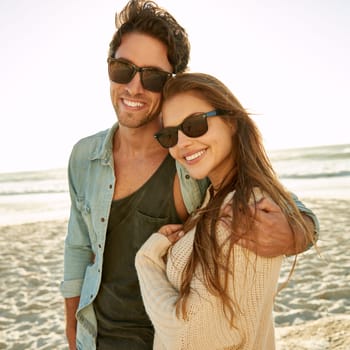 Sun, sea and romance. Portrait of a loving young couple wearing sunglasses standing together on the beach