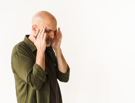 Mature man experiencing headache holds head with both hands. Concept of headache, conveying pain and discomfort that can accompany such experience. . High quality photo