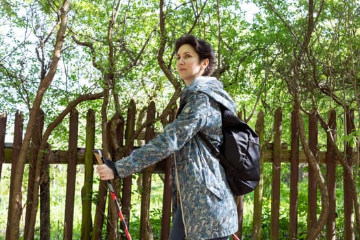 Nordic walking. Young Caucasian Woman Walks With Sticks, Trekking Poles And Backpack, Physical Activity In Countryside . Sports Tourism, Outdoor Recreation. Horizontal Plane High quality photo