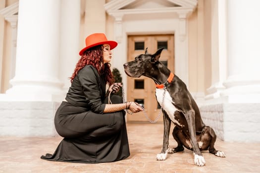 A photo of a woman and her Great Dane walking through a town, taking in the sights and sounds of the urban environment.