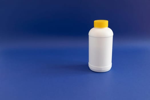 White Plastic Bottle, Yellow Cap With Pipe Granules Cleaner On Purple Blue Background. Removal Of Blockage In Sink, Shower With Special Chemicals. Cleaning Clog In Kitchen,Bathroom. Copyspace For Text