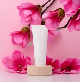 White plastic tube for liquid cosmetics on a pink background, packaging