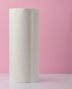 Roll of white kitchen towels on a pink background