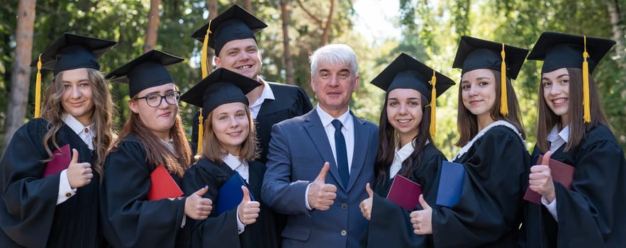 University professor and seven students rejoice at graduation and show thumbs up outdoors