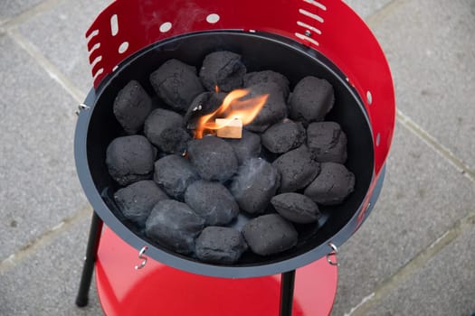 a man lights a fire with a lighter special charcoals for a barbecue a barbecue house on the terrace prepares a place for a barbecue. High quality photo