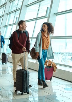 Travel, love and smile with interracial couple in airport for vacation, tourism and departure. International trip, luggage and holiday with man and black woman walking for flight, journey or airline.