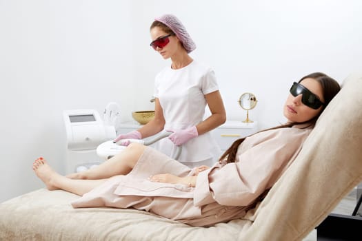 Woman receiving laser hair removal epilation on legs in beauty salon