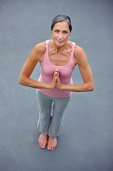 Doing yoga for a healthy body and mind. High angle portrait of an attractive mature woman doing yoga outdoors