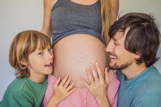 Father and elder son listen to mom's pregnant belly.