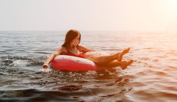 Woman summer sea. Happy woman swimming with inflatable donut on the beach in summer sunny day, surrounded by volcanic mountains. Summer vacation concept