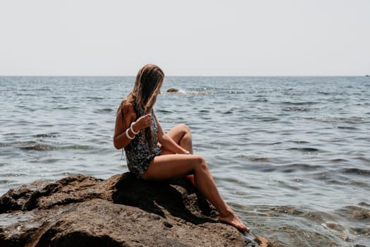 Woman travel sea. Young Happy woman in a long red dress posing on a beach near the sea on background of volcanic rocks, like in Iceland, sharing travel adventure journey