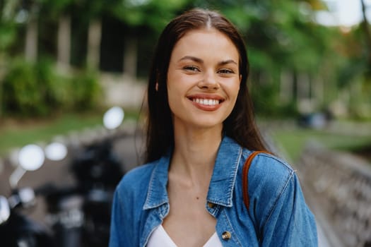 Portrait of a woman brunette smile with teeth walking outside against a backdrop of palm trees in the tropics, summer vacations and outdoor recreation, the carefree lifestyle of a freelance student. High quality photo