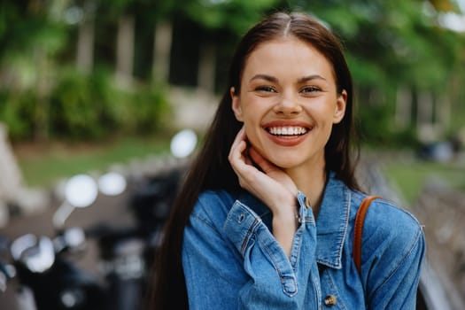 Portrait of a woman brunette smile with teeth walking outside against a backdrop of palm trees in the tropics, summer vacations and outdoor recreation, the carefree lifestyle of a freelance student. High quality photo