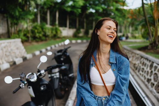 Portrait of a woman brunette smile with teeth walking outside against a backdrop of palm trees in the tropics, summer vacations and outdoor recreation, the carefree lifestyle of a freelance student. High quality photo