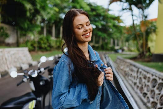 Portrait of a woman brunette smile with teeth walking outside against a backdrop of palm trees in the tropics, summer vacations and outdoor recreation, the carefree lifestyle of a freelance student. High quality photo