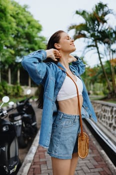 Portrait of a woman brunette smile with teeth walking outside against a backdrop of palm trees in the tropics, summer vacations and outdoor recreation, the carefree lifestyle of a freelance student. High quality photo