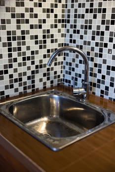 Clean sink with pouring water in the kitchen, metal faucet and sink in an old home interior. High quality photo