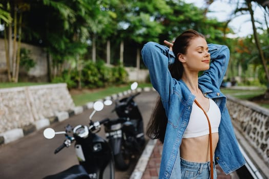 Portrait of a woman brunette smile with teeth walking outside against a backdrop of palm trees in the tropics, summer vacations and outdoor recreation, the carefree lifestyle of a freelance student. High quality photo