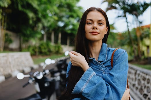 Portrait of a woman brunette smile with teeth walking outside against a backdrop of palm trees in the tropics, summer vacations and outdoor recreation, the carefree lifestyle of a freelance student. High quality photo