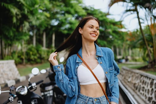 Portrait of a woman brunette smile with teeth walking outside against a backdrop of palm trees in the tropics, summer vacations and outdoor recreation, the carefree lifestyle of a freelance student. High quality photo