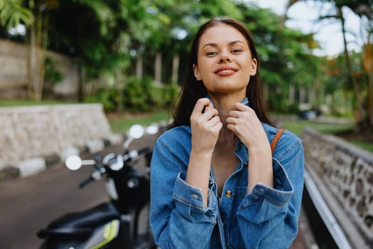 Portrait of a woman brunette smile with teeth walking outside against a backdrop of palm trees in the tropics, summer vacations and outdoor recreation, the carefree lifestyle of a freelance student. High quality photo